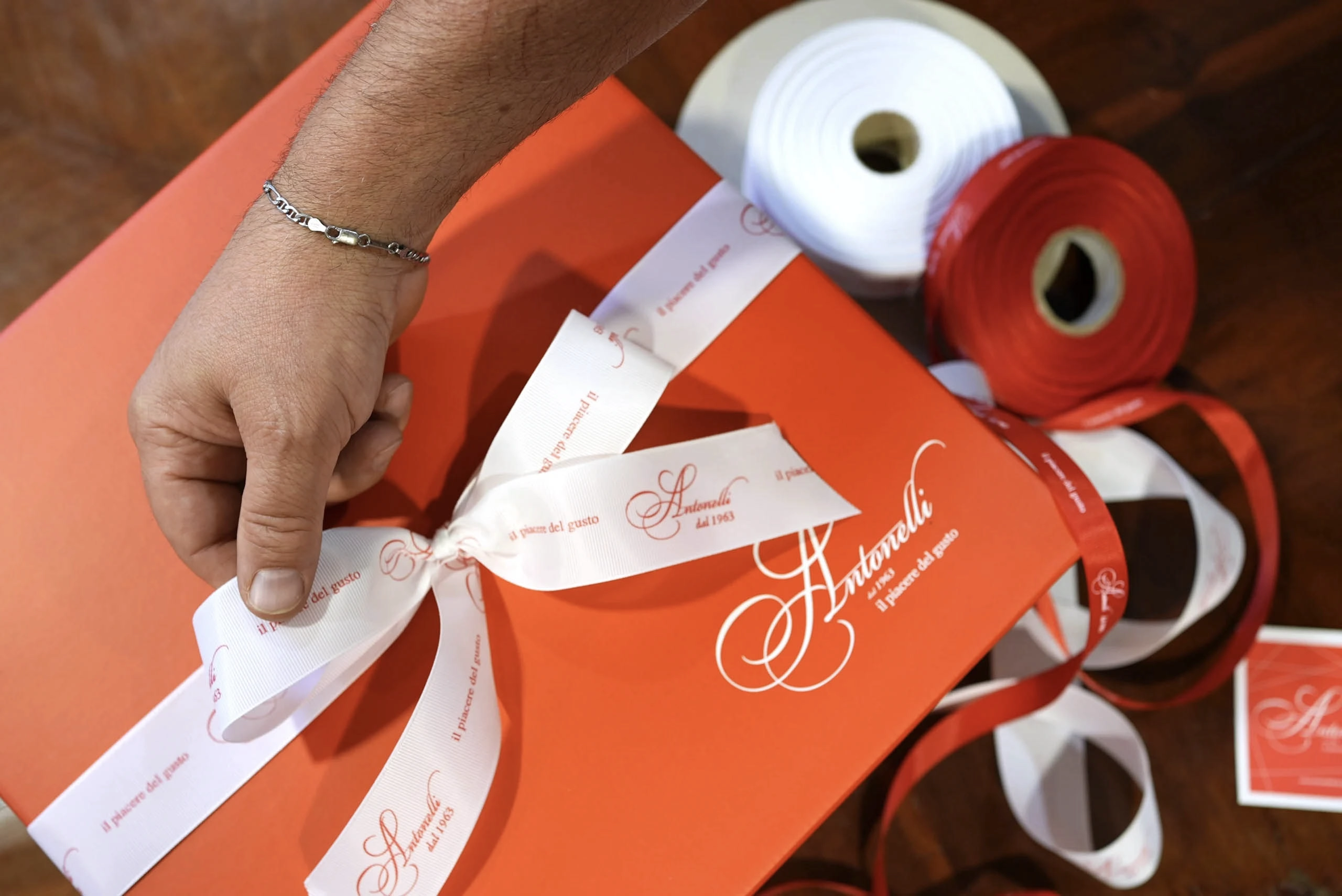 Personalizzazione di un regalo aziendale alimentare di Natale con scatola regalo e nastro brandizzato Antonelli.
